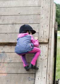 Rear view of girl climbing on wood