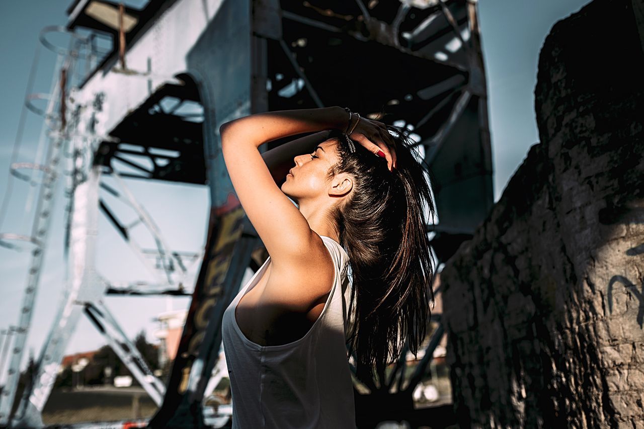 CLOSE-UP OF YOUNG WOMAN STANDING ON WALL