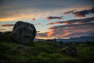 Rocks on landscape against cloudy sky