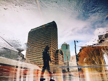 Upside down image of man and buildings reflection on puddle