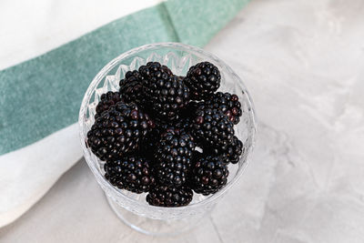 Fresh blackberries in a patterned glass bowl on gray background