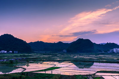 Scenic view of agricultural landscape against sky during sunset