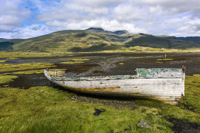 Abandoned boat on land against sky