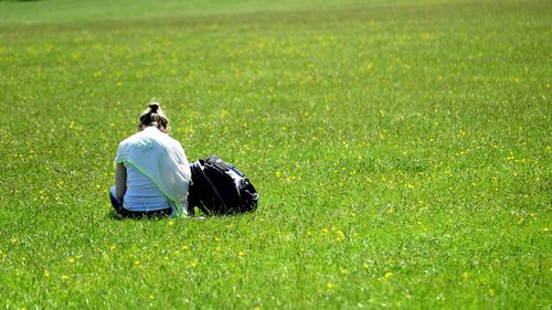 Rear view of man sitting on grassy field