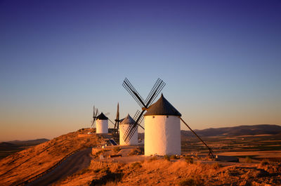 Traditional windmills on field against clear sky