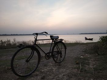 Bicycles on beach against sky during sunset