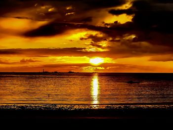 Scenic view of sea against dramatic sky during sunset