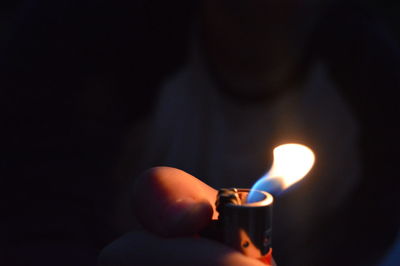 Close-up of hand holding illuminated candle