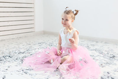 Portrait of a girl sitting on pink wall