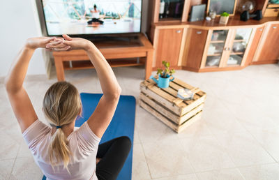 High angle view of woman with arms raised exercising at home