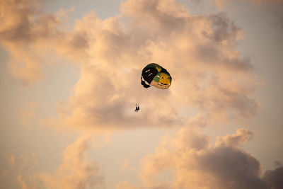 Low angle view of person parasailing against sky during sunset