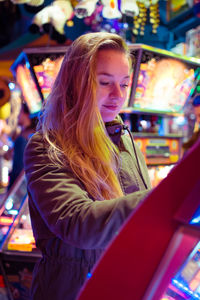 Smiling young woman standing in illuminated market at night