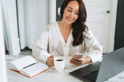 Young woman using digital tablet while sitting on table