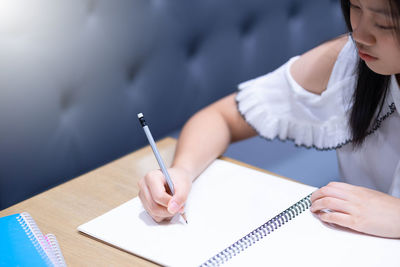 High angle view of girl writing in book