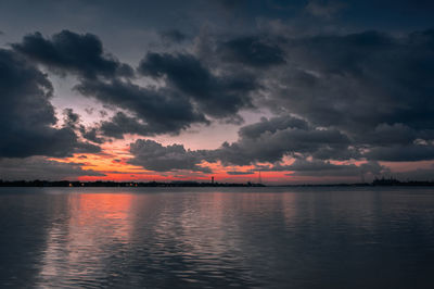 Scenic view of lake against dramatic sky during sunset