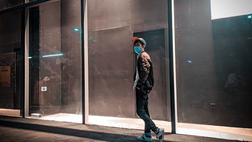 Man standing by glass wall in city