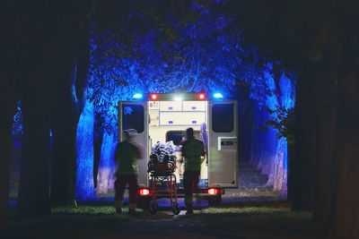 Doctors and patient by ambulance in forest at night