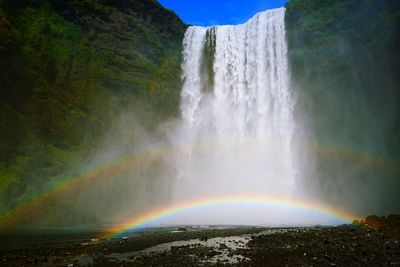 Scenic view of rainbow over waterfall