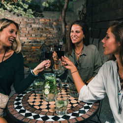 Female friends toasting wineglasses at outdoors restaurant during night