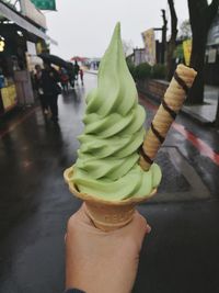 Close-up of hand holding ice cream in city