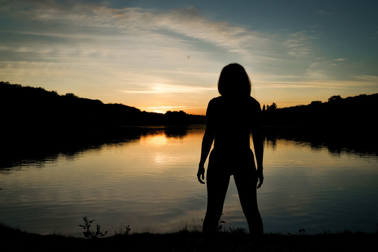 sunset, silhouette, sky, water, one person, beauty in nature, lake, reflection, standing, tranquil scene, scenics - nature, tranquility, real people, nature, cloud - sky, orange color, rear view, leisure activity, non-urban scene