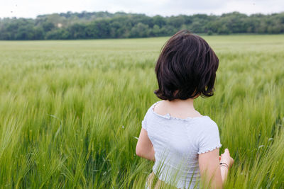 Back view of child in white top walking in a vast field of wheat