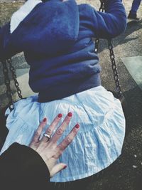 Cropped image of mother pushing girl on swing at playground