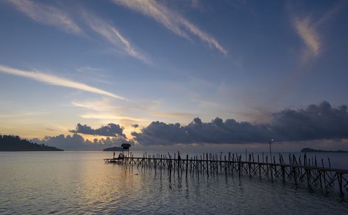 Pier on sea against sky at sunset