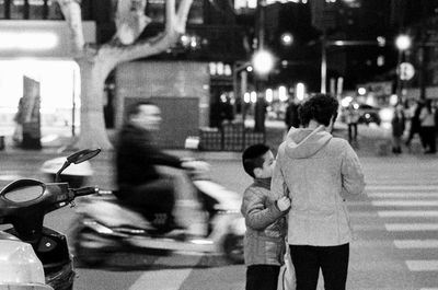 Rear view of people crossing road at night