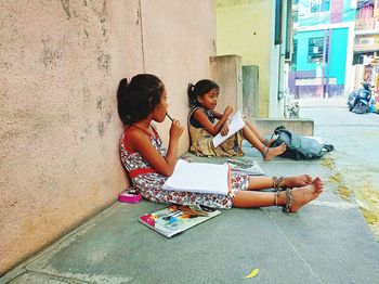 Women sitting on floor against wall