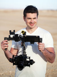 Man holding camera looking away while standing on field