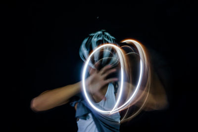 Man making light painting while standing against black background