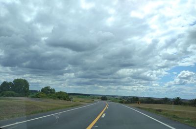 Empty road against cloudy sky