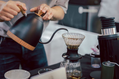 Barista pour hot water on rough brown bubbles coffee through drip filter