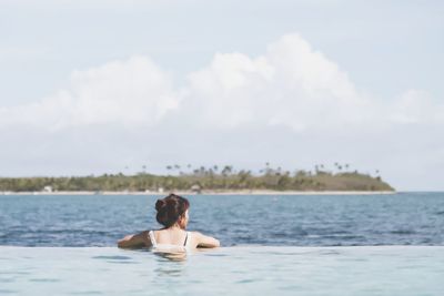 Woman in swimming pool by sea against sky