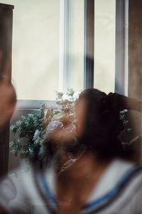 Portrait of woman holding glass window