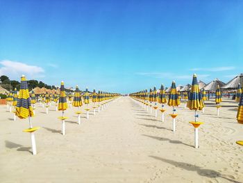 Row of umbrellas on beach against blue sky