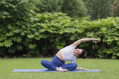 Full length of young woman lying on grass against plants