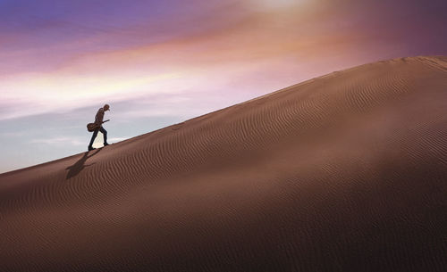 Rear view of man walking on sand at desert