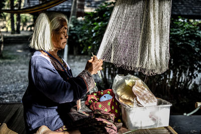 Side view of woman knitting fishing net