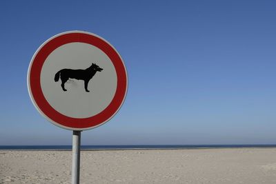 Close-up of road sign on beach against clear blue sky