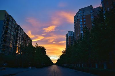 Road passing through city at sunset