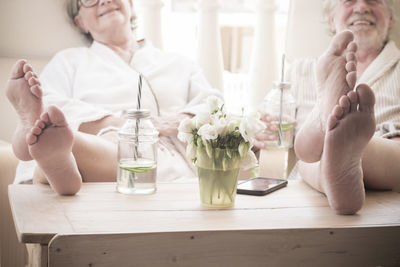 Midsection of couple sitting on table at home