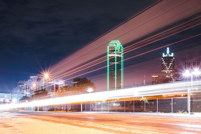 Light trails on city street against illuminated buildings at night