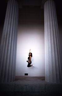 Full length of woman jumping against white wall
