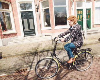 Side view of woman riding bicycle on road during sunny day