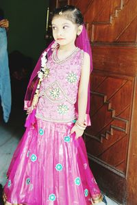 Girl wearing dress standing against wall