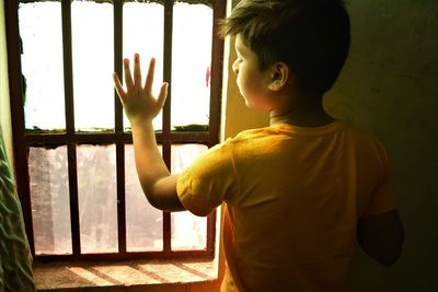 Rear view of boy looking at window