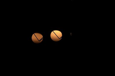 Low angle view of illuminated light bulb against black background