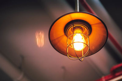 Low angle view of illuminated light bulb hanging from ceiling